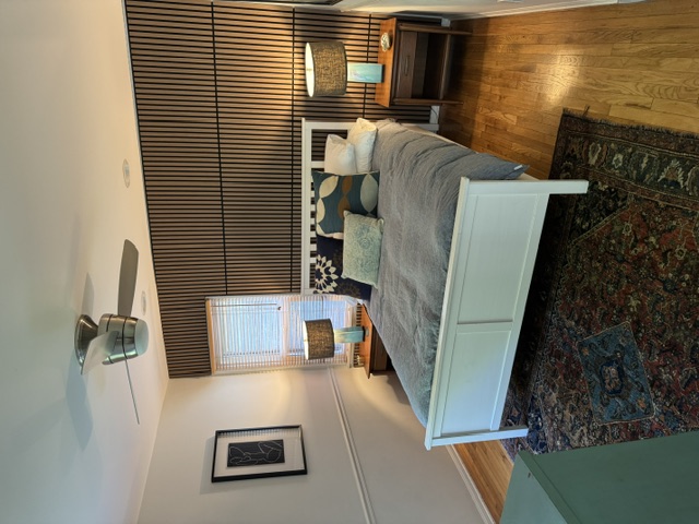 Primary bedroom with a queen bed, warm bedside lighting and a wood-slat feature wall